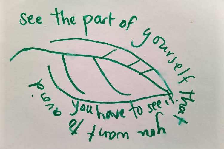 An index card on which the words "se the part of yourself that you want to avoid, you have to see it" are written around a sketch of a leaf in green marker.